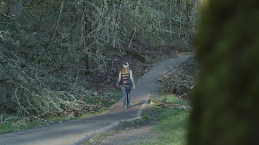 Woman walks on the cycle path in the forest