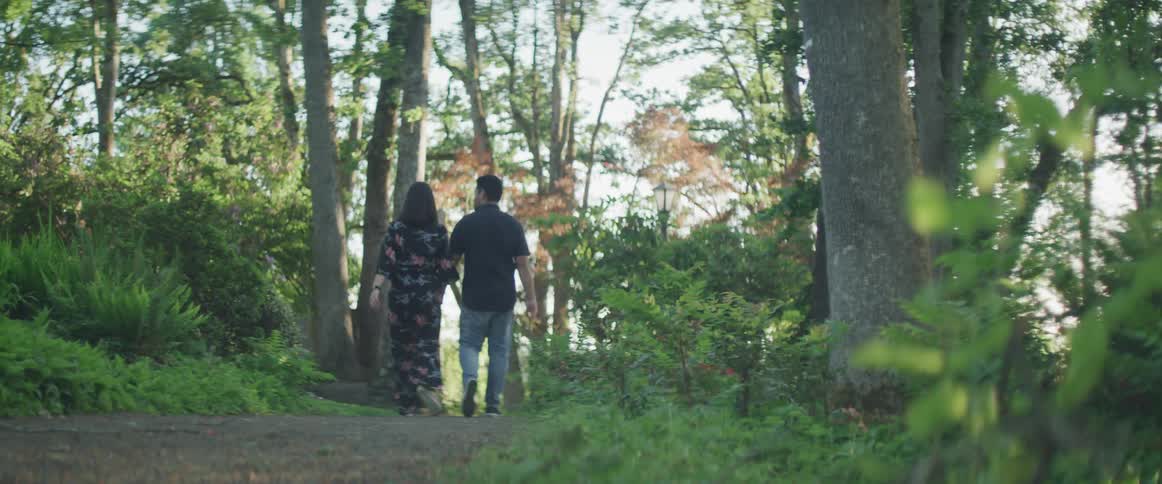 A man and a woman walking down a path in the woods