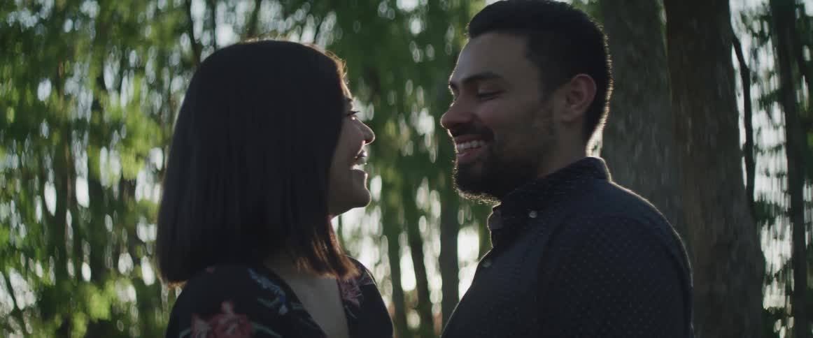Young couple smiling and laughing at each other in forest at sunset