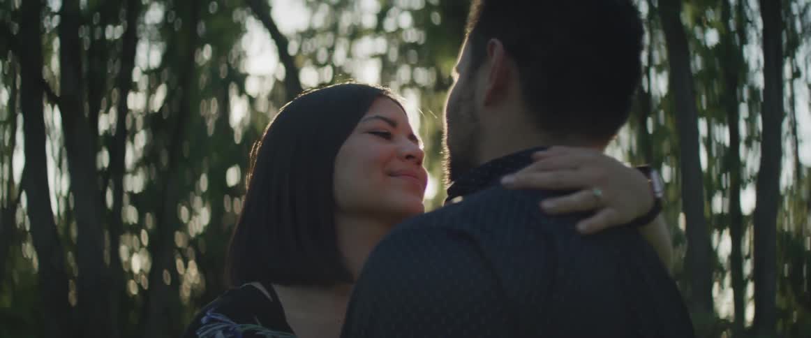 A man and woman dance while gazing into each others eyes near trees