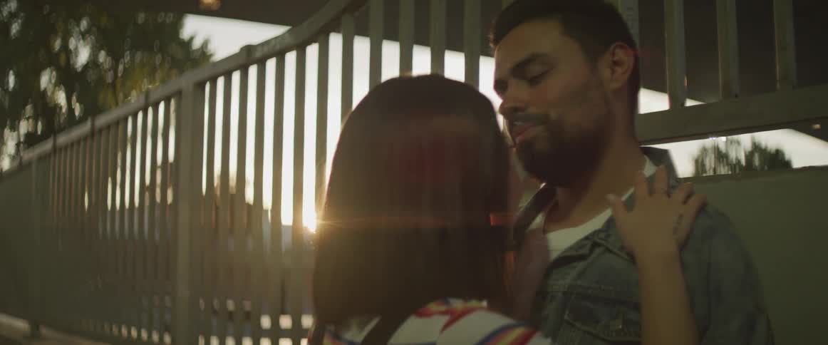 A man kisses a womans forehead while they hug outside at sunset