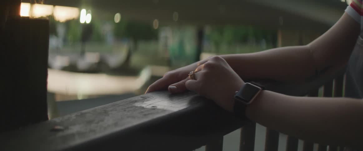 A womans hands on a railing with a skate park in the background