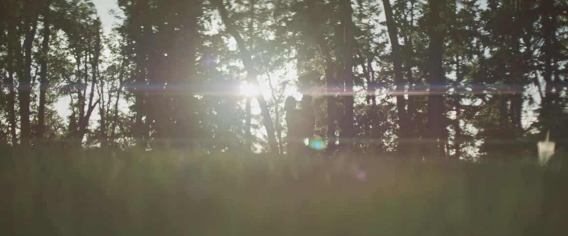A couple dances under the trees