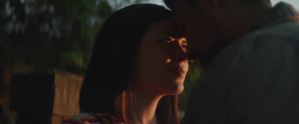 A man and woman lean head to head in the yard