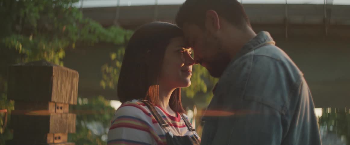 A man and a woman standing outside with their foreheads touching