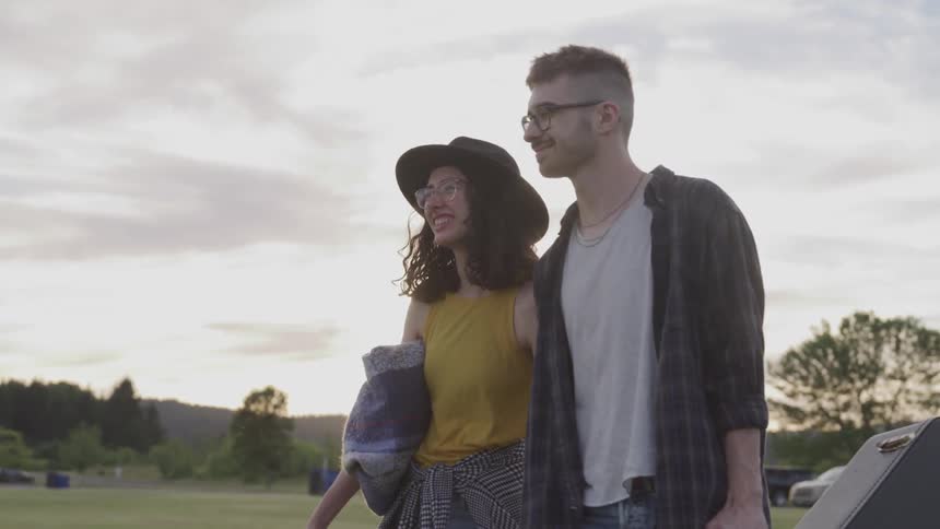 A young couple walk across a grassy field
