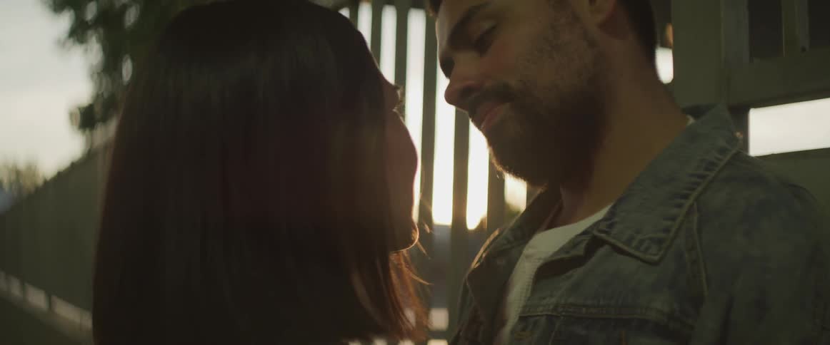 A man and woman gaze into each others eyes outside at sunset