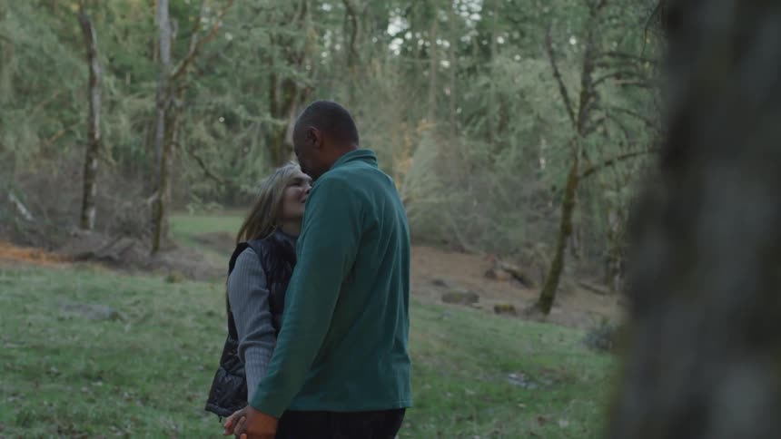 Black and blonde woman hold each other in the forest