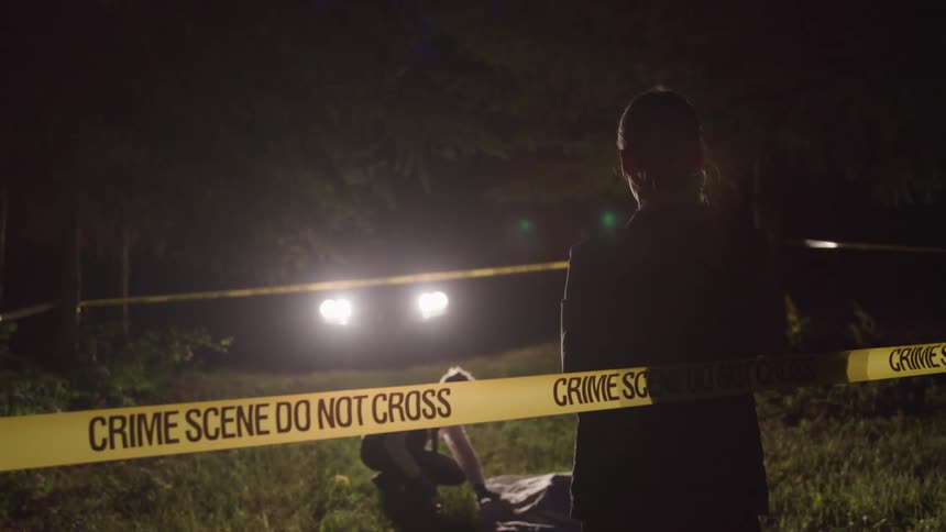 Male and female at a crime scene at night investigating dead body