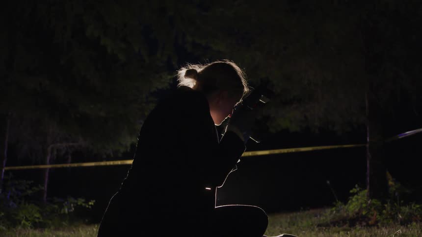 A young female police officer takes pictures at a crime scene