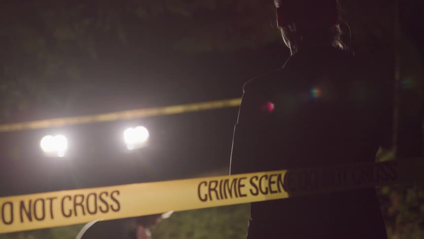 Two police officers inspect a crime scene at night