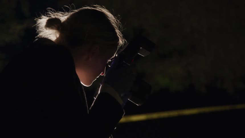 A young woman takes pictures at a crime scene