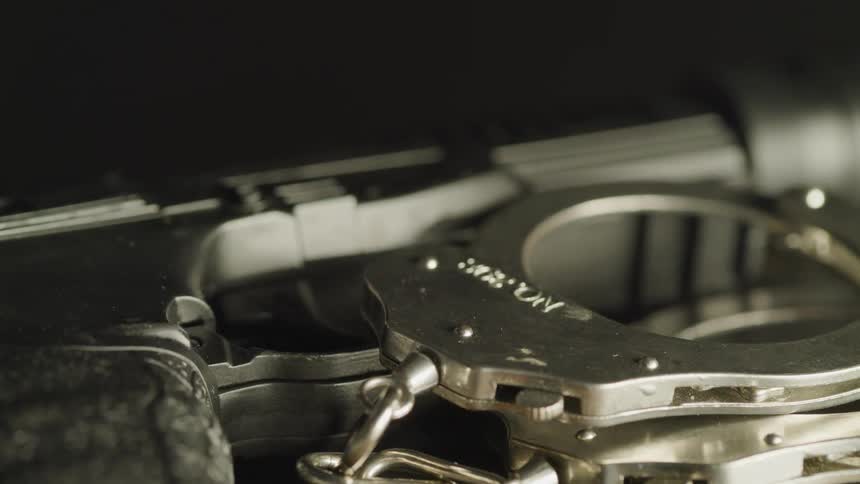 Metal handcuffs sit next to a handgun