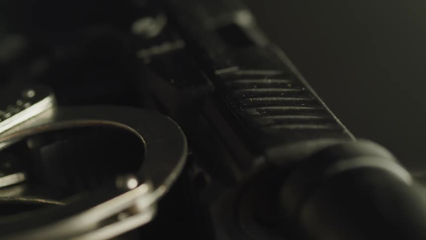 Handcuffs lay against a gun barrel