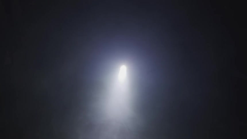 Smoke blows in front of a light in the distance