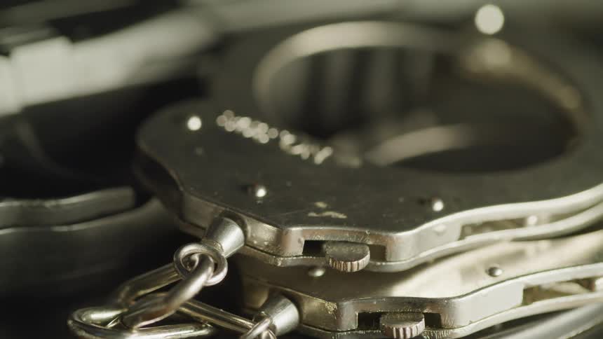 Metal handcuffs beside a handgun