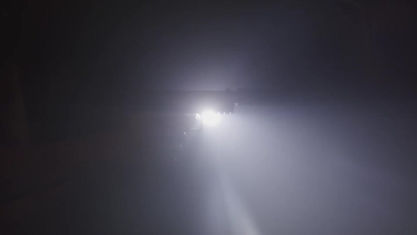 The silhouette of a handgun is seen as it is held up in front of a bright light in a dark room