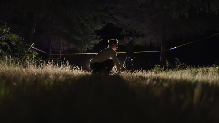 A police detective crouches down to investigate a crime scene