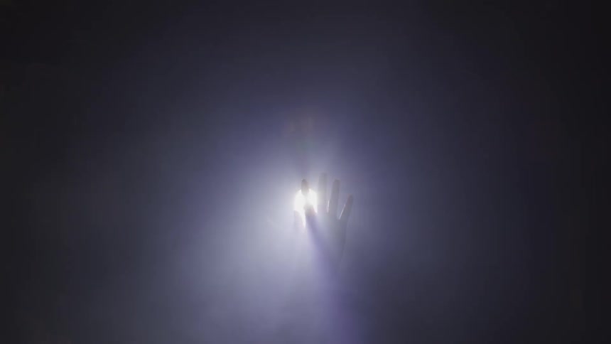 A person waves their hand in front of a light