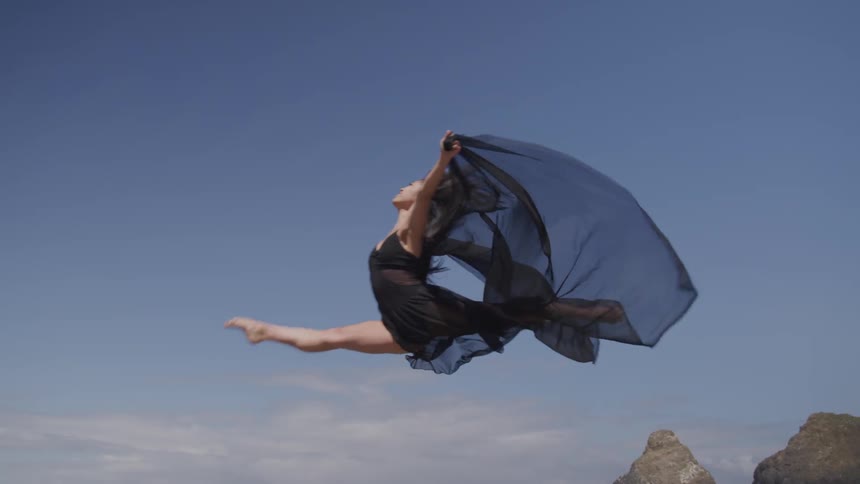 A woman in a black shawl dancing on the beach