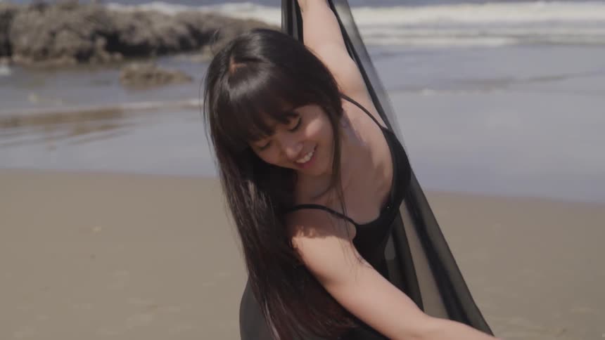 A woman in black dancing in the beach
