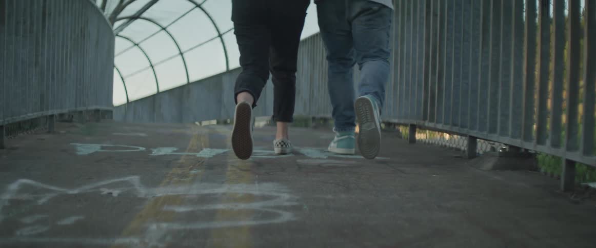 Two people walk over the overpass together