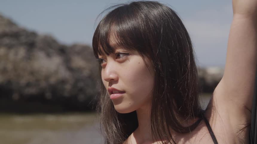 A woman is standing near the ocean moving her arms