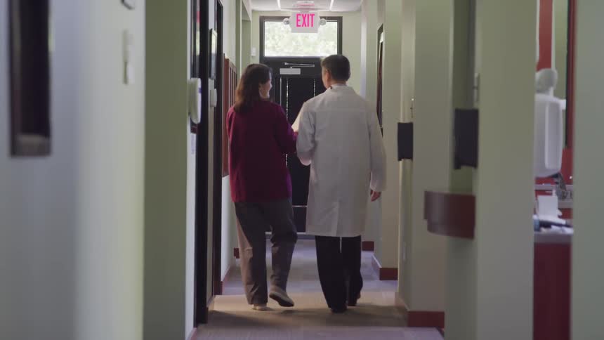 Doctor and aide walk down the corridor