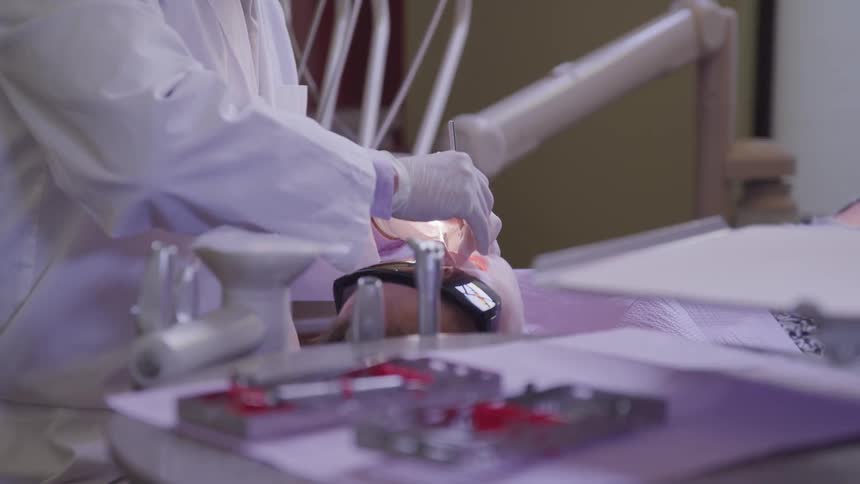 A dentist works on a patients teeth in an office