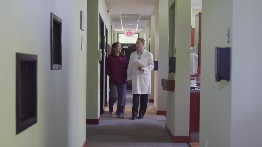 A doctor and patient walking down a hallway