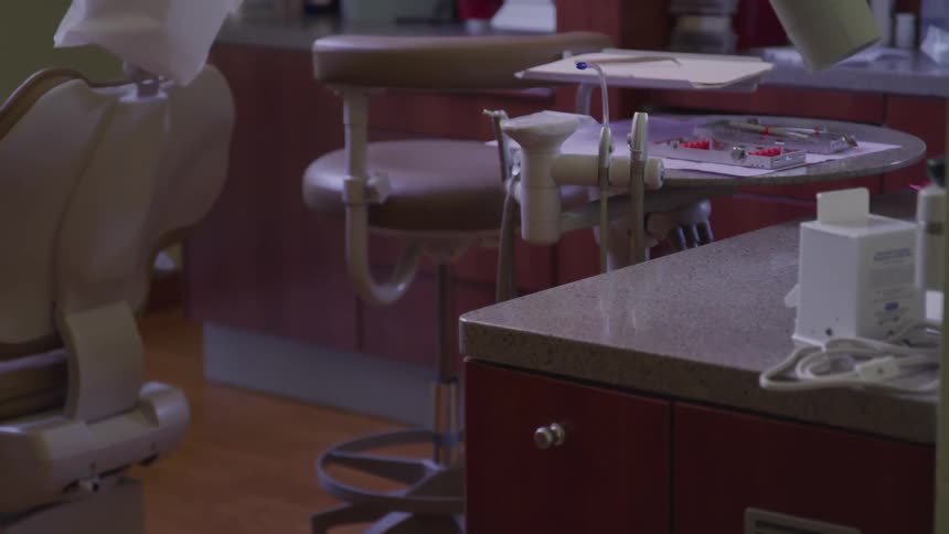 A dentist office with a chair and medical tool tray