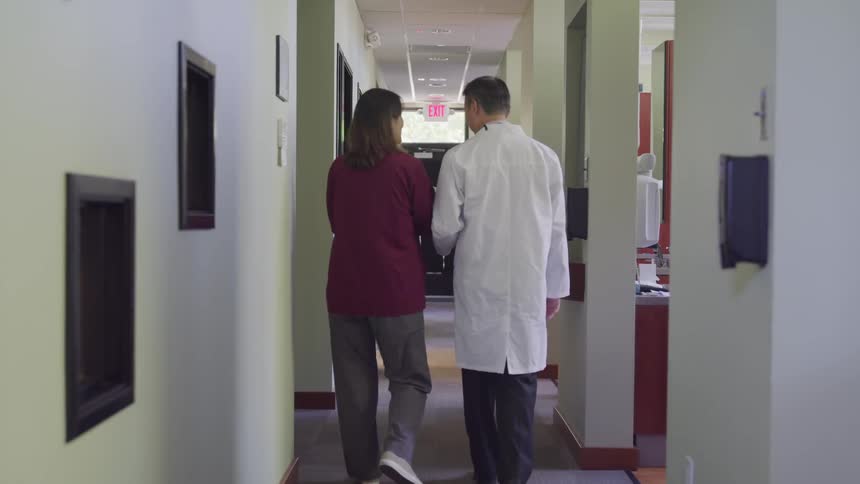 Woman walks down a hallway with a doctor