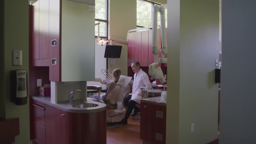 Dentist talks to patient sitting in exam seat