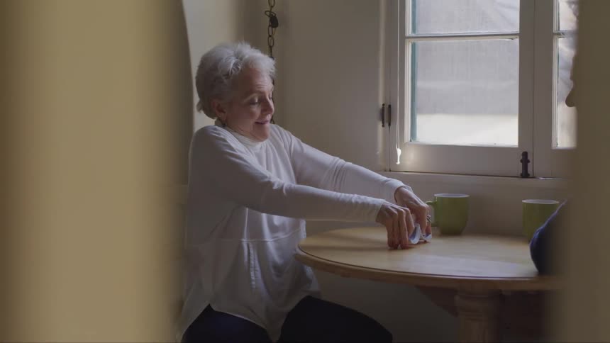 An elderly couple gets ready to play cards on a wooden table