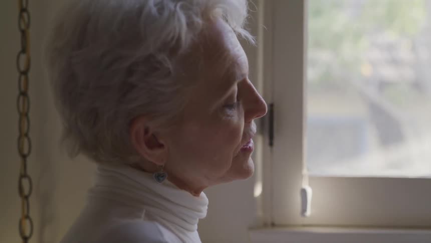 An elderly woman looking out a window