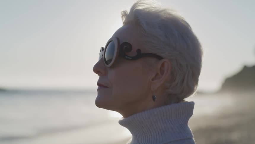 The profile of a beautiful older woman on the beach looking out at the ocean
