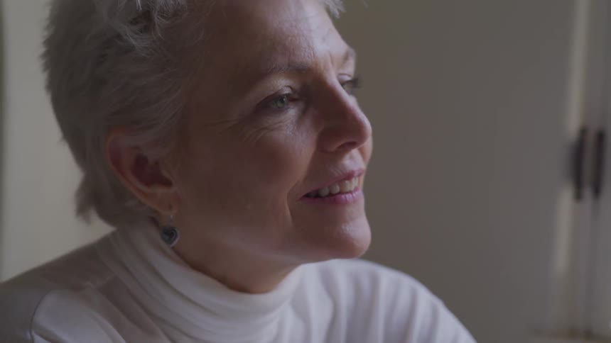 An elderly woman smiles and nods her head