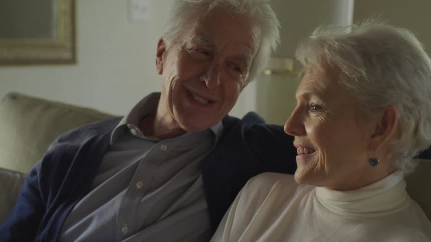 Elderly couple sitting on couch talking to each other