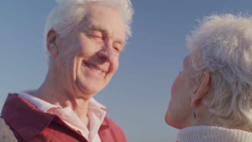 An elderly man and woman smile and talk together