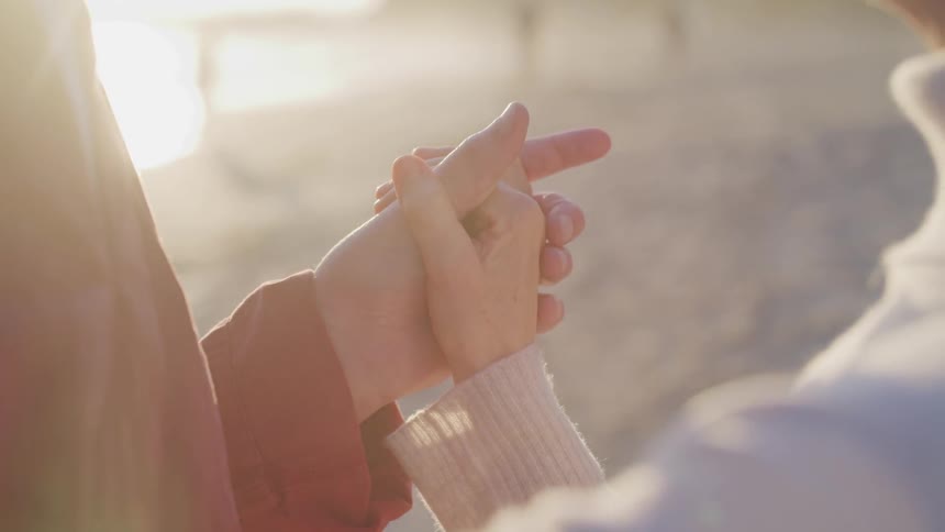 A man and woman hold hands on a beach