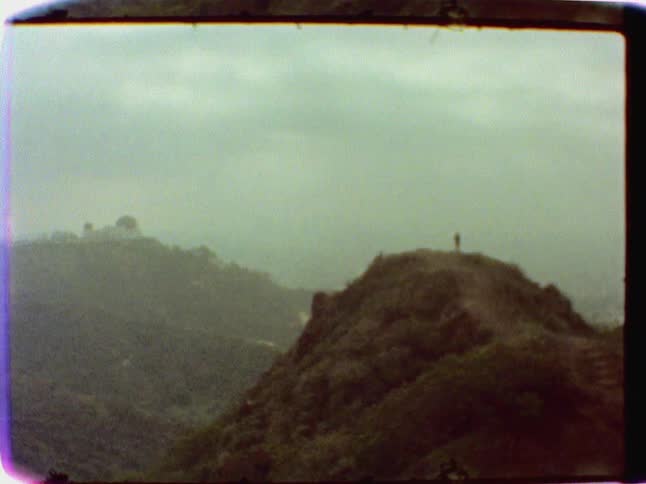 A person stands on a hill on a cloudy day