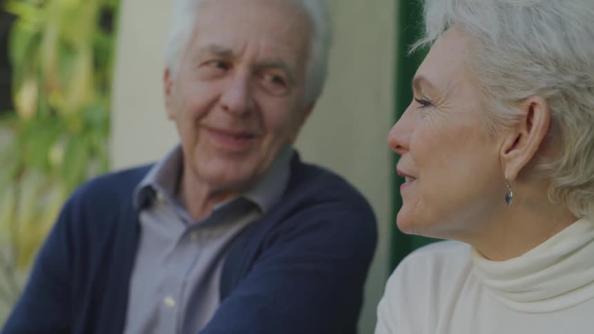 An elderly man and woman sit and talk together