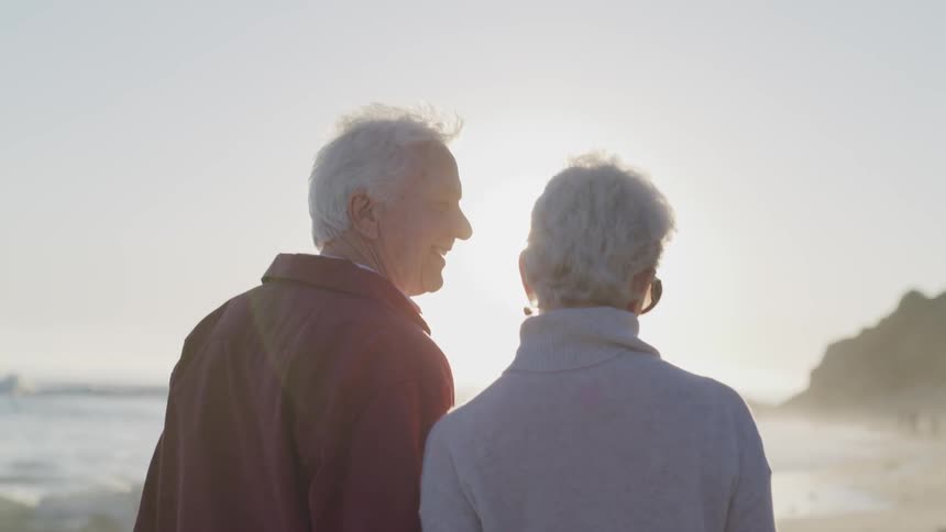 Elderly man and woman walk on the beach on a sunny day