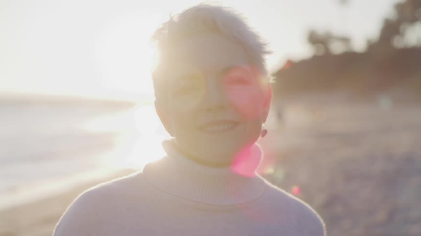 A woman on the beach staring and smiling