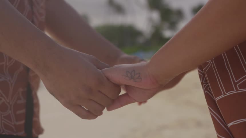 A man and woman standing face to face holding hands