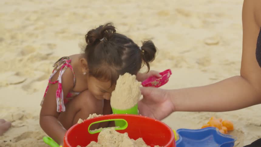 A young girl plays in the sand with her parents