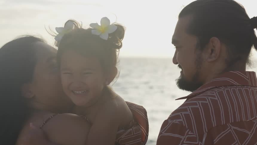 Parents hold their child by the water