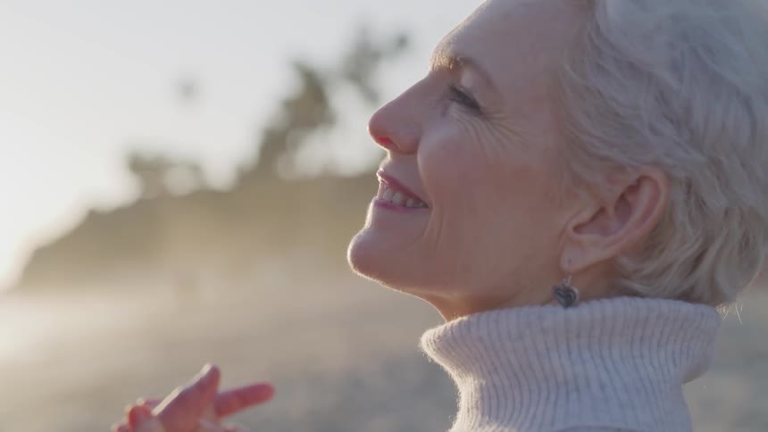 An elderly couple smiles while gazing into each others eyes outside on a sunny day