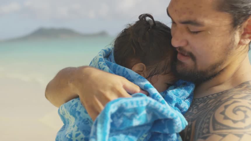 A man holding a small child at the beach