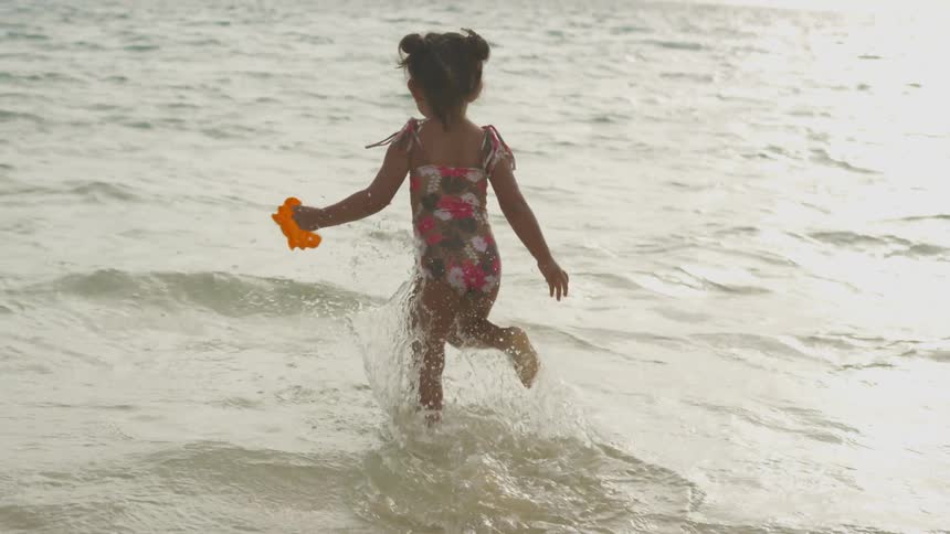 A little girl runs in to the water